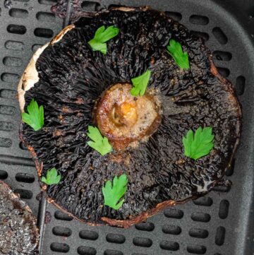 Overhead view of an air fryer portobello mushroom in the basket with parsley on top.