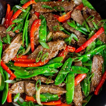 Overhead view of beef with oyster sauce with veggies in a large cast iron pan.