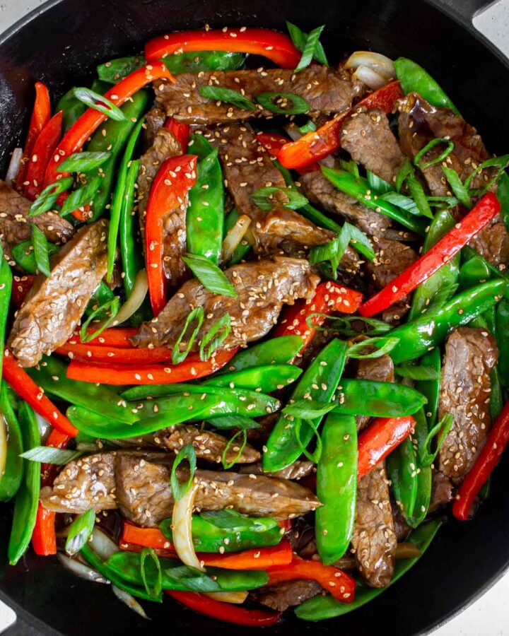 Overhead view of beef with oyster sauce with veggies in a large cast iron pan.