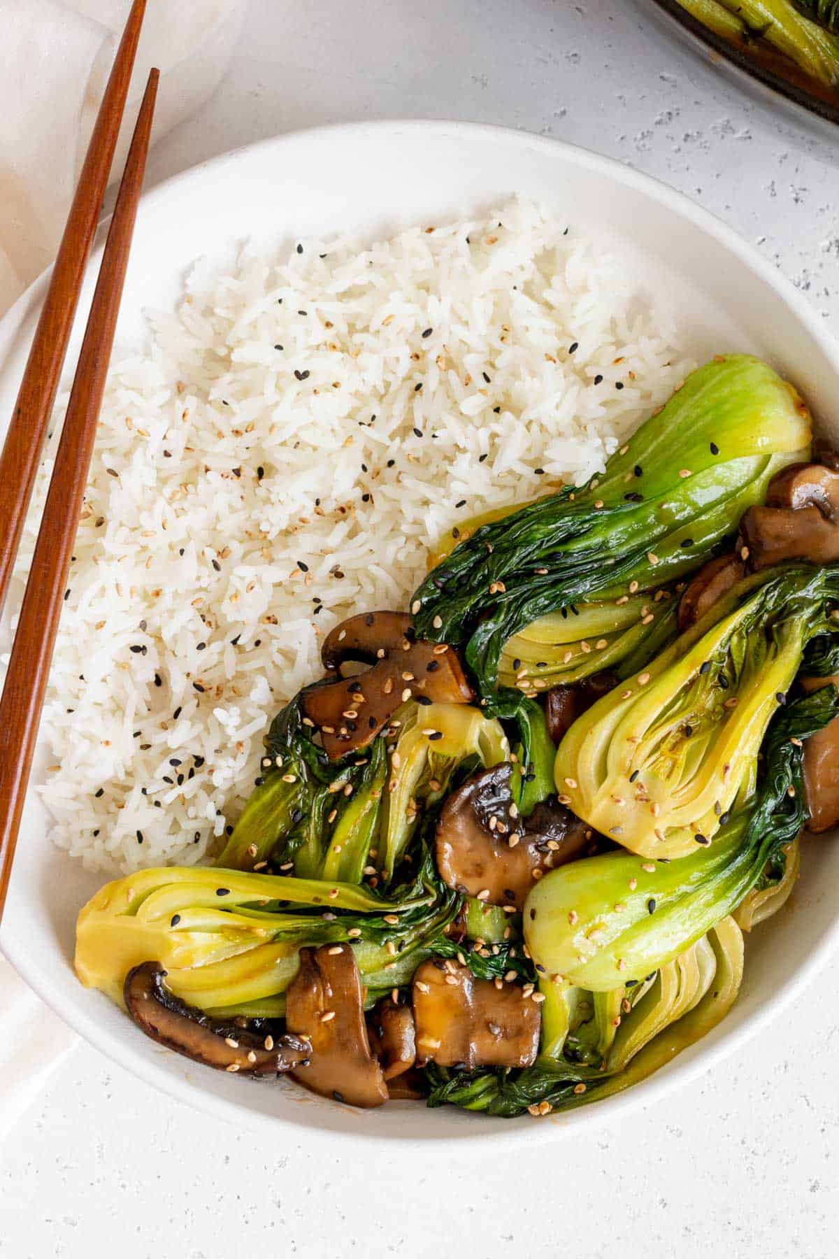 Close up view of a plate with bok choy stir fry over white rice.