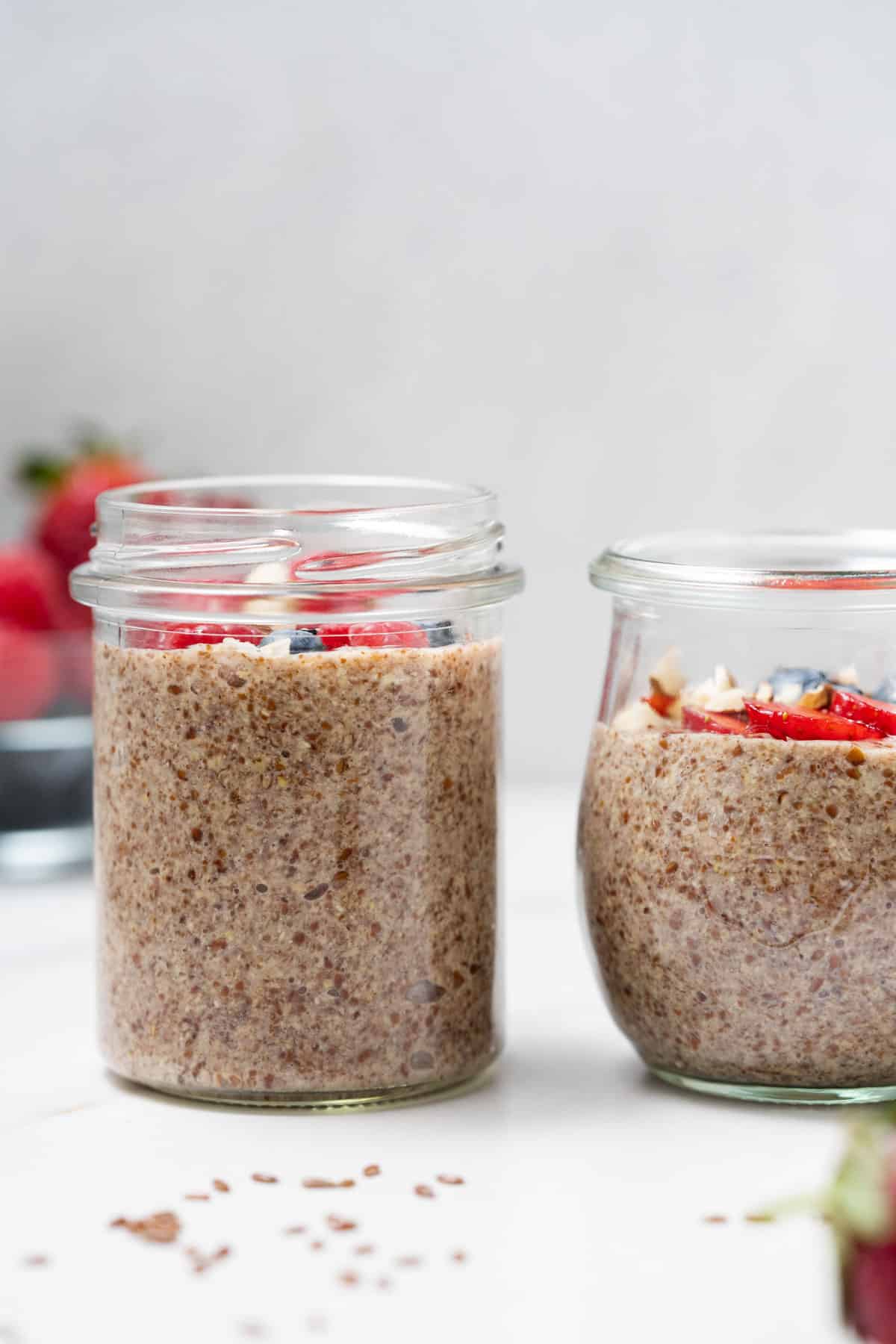 Two different jars of flaxseed pudding with diced fruit on top.