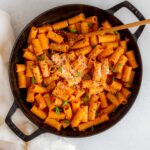 Overhead view of a skillet of gochujang pasta topped with green onions and parmesan.