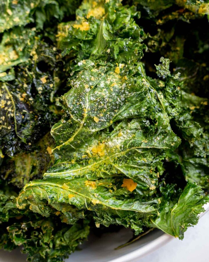 Close up view of kale chips with nutritional yeast.