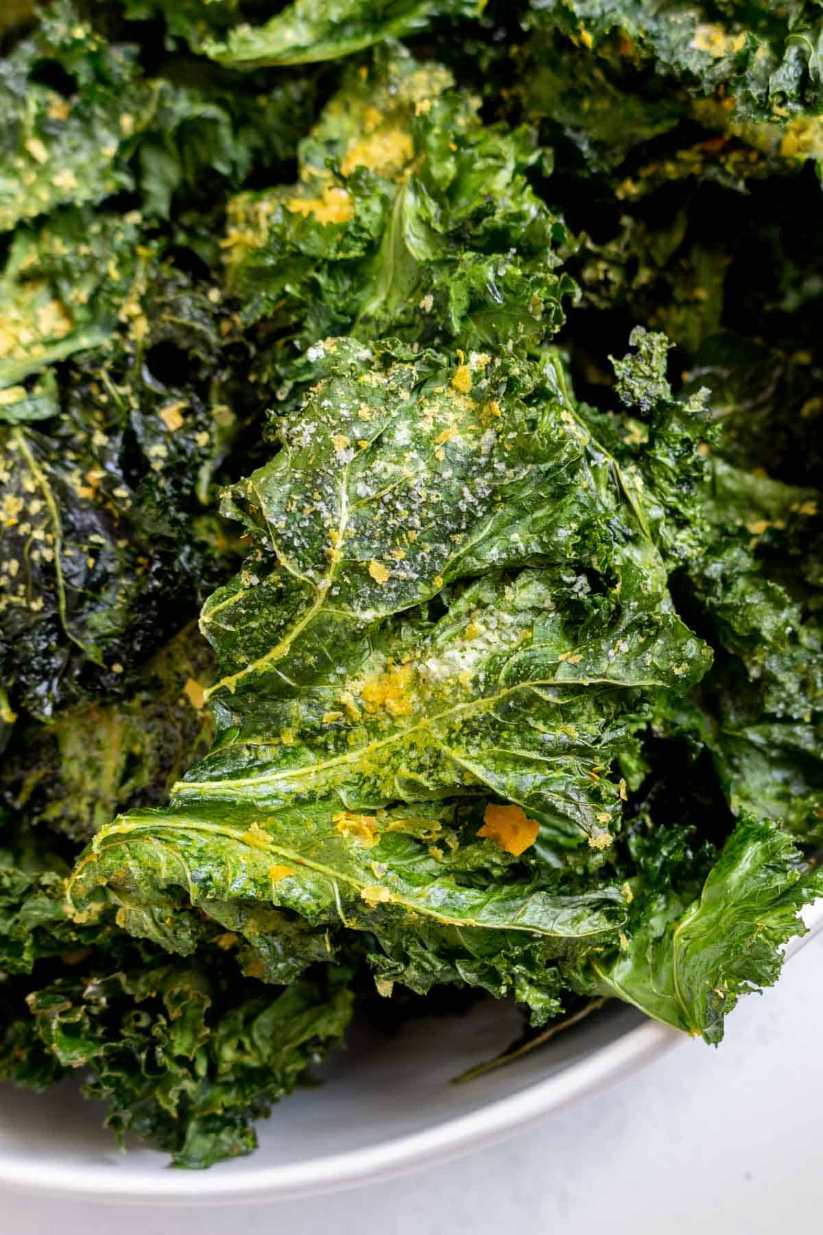 Close up view of kale chips with nutritional yeast.
