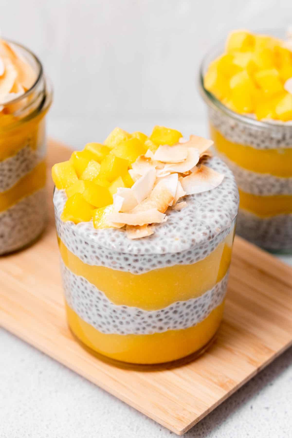 An angled view of a jar of mango chia pudding with shredded coconut and diced mango on top.
