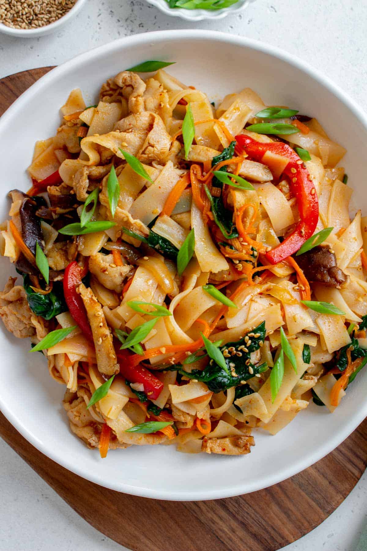 Overhead view of a plate with spicy pork noodles with spinach, carrots, bell pepper, and mushrooms.