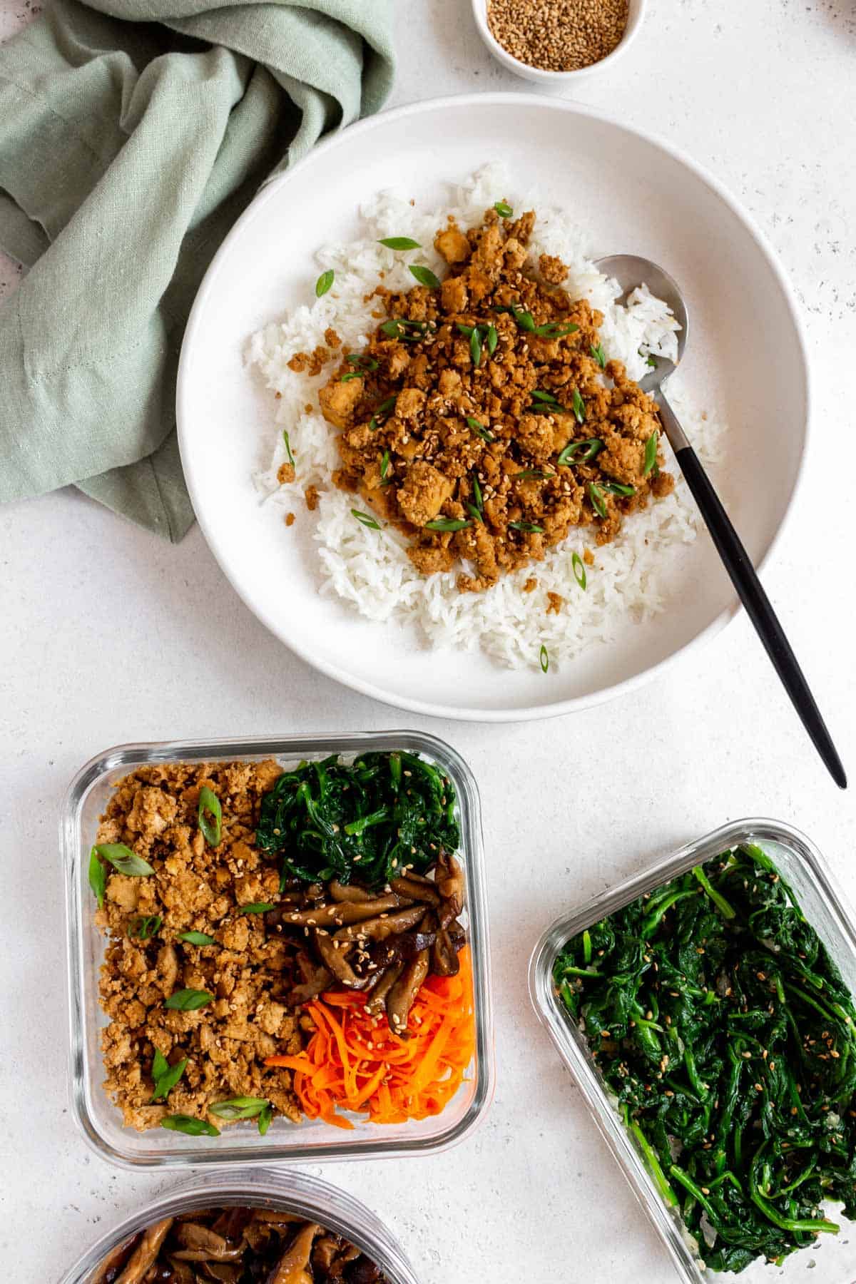 A plate with rice and tofu bulgogi beside a meal prep container of tofu bulgogi.