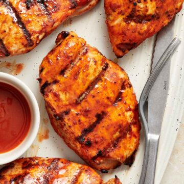 Overhead view of a focused view of a grilled buffalo chicken breast on a platter with more.