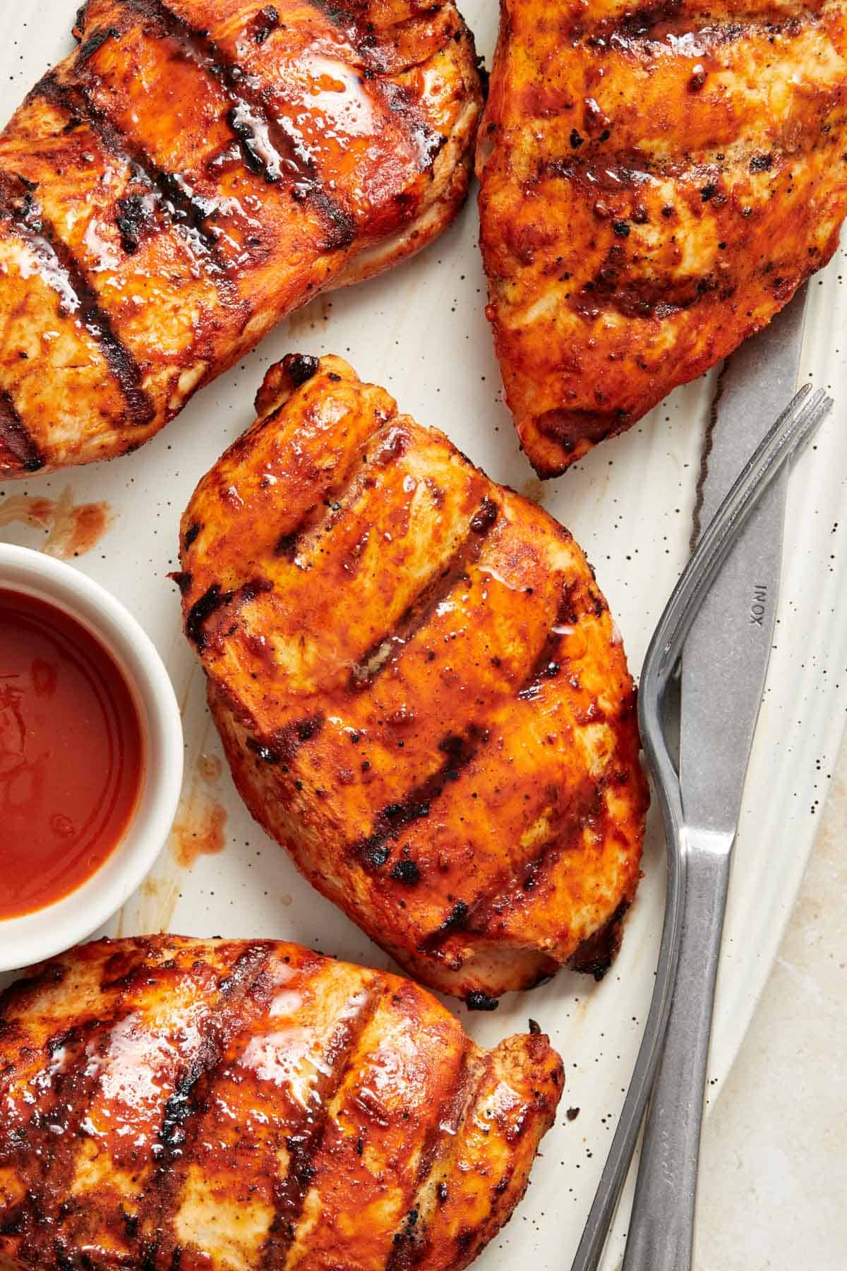 Overhead view of a focused view of a grilled buffalo chicken breast on a platter with more.