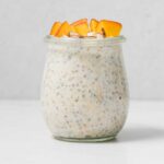 A jar of high protein overnight oats with peaches on top.