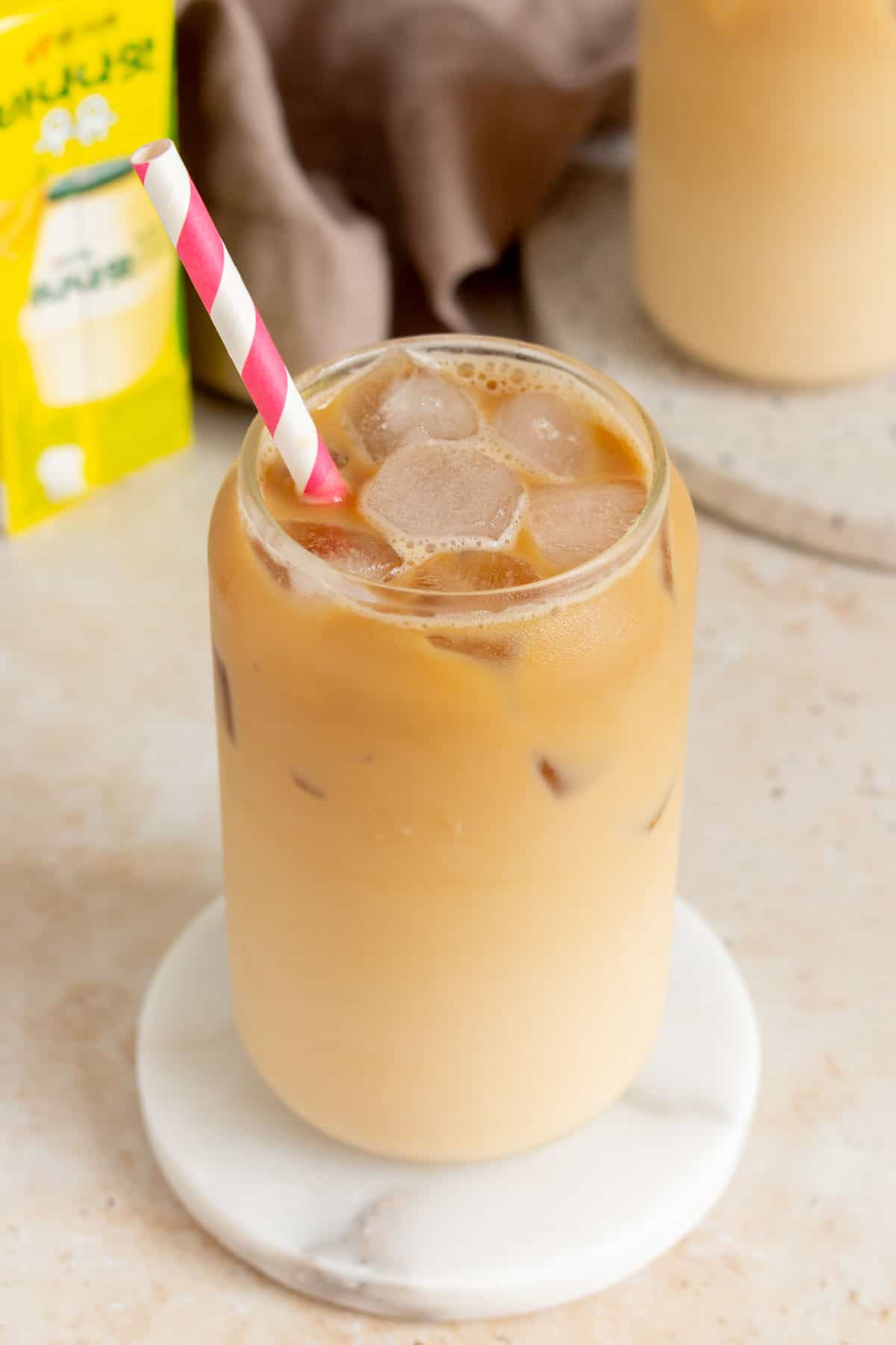 An angled view of a glass of iced banana latte.
