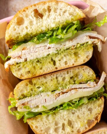 Two pesto turkey sandwiches, facing upwards, showing the interior.