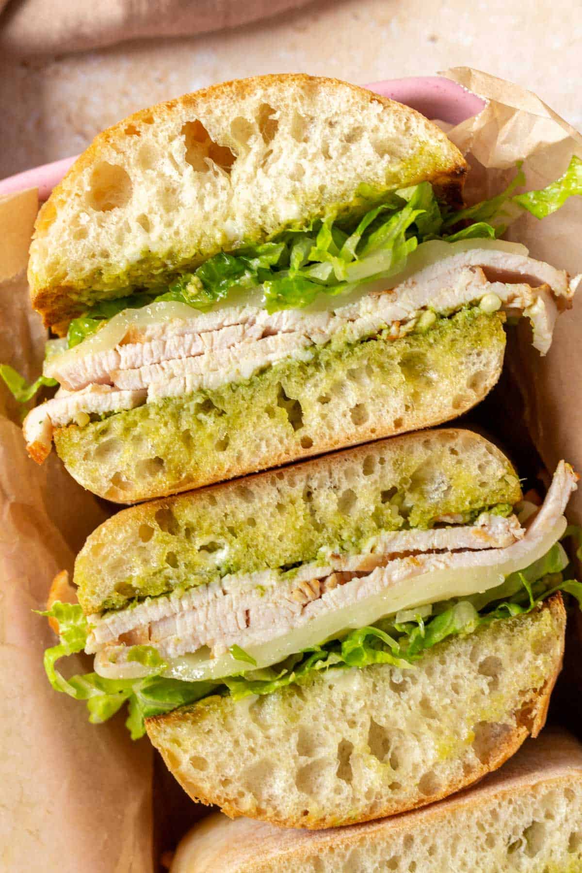 Two pesto turkey sandwiches, facing upwards, showing the interior.