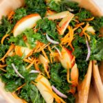 A close up view of a large bowl of kale and apple salad.