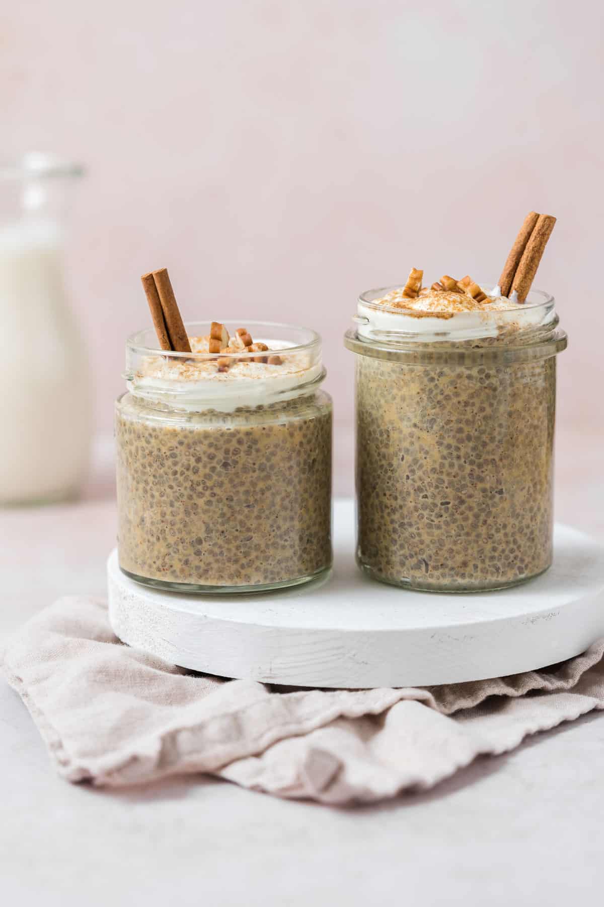 Two jars of pumpkin chia pudding on a serving tray.