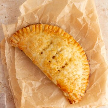 A pumpkin pasty on crinkled brown parchment paper.