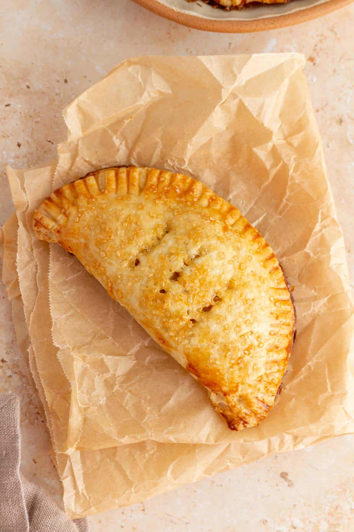 A pumpkin pasty on crinkled brown parchment paper.