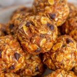 Close up view of pumpkin protein balls stacked on top of each other on a plate.