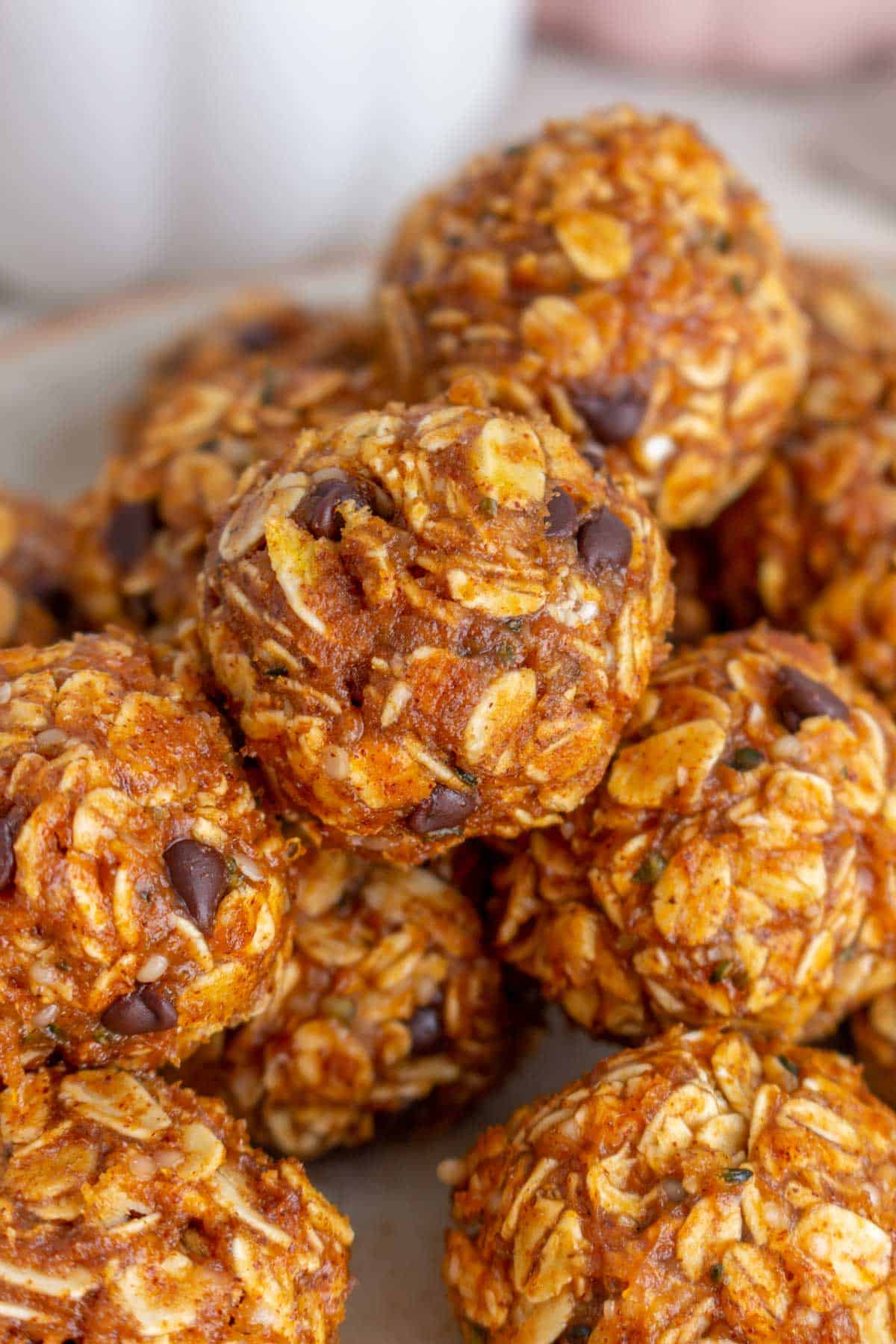Close up view of pumpkin protein balls stacked on top of each other on a plate.