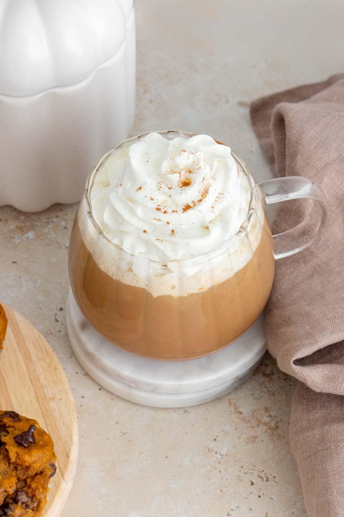 A mug of pumpkin spice latte with whipped cream on top with a sprinkle of pumpkin pie spice.