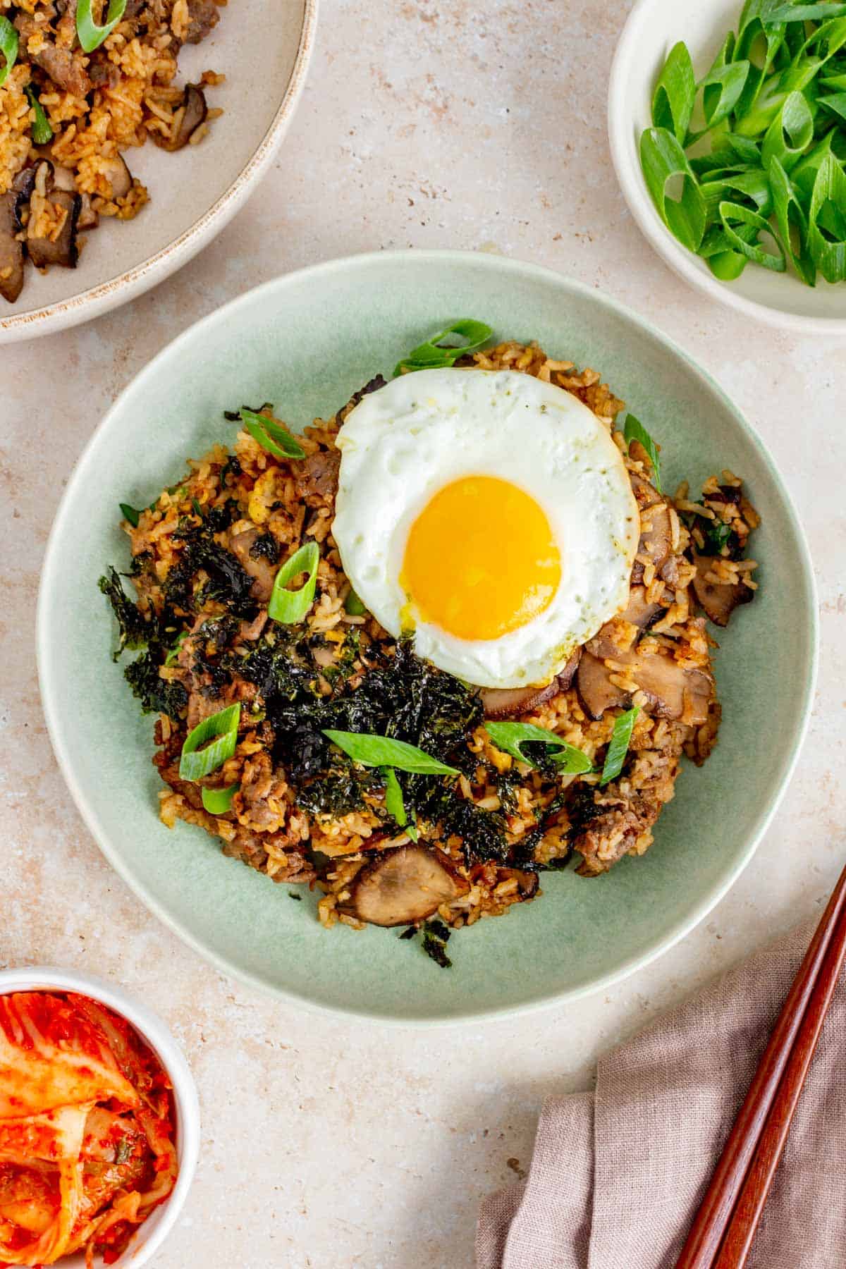 An overhead view of a plate of bulgogi fried rice topped with seaweed and a fried egg.