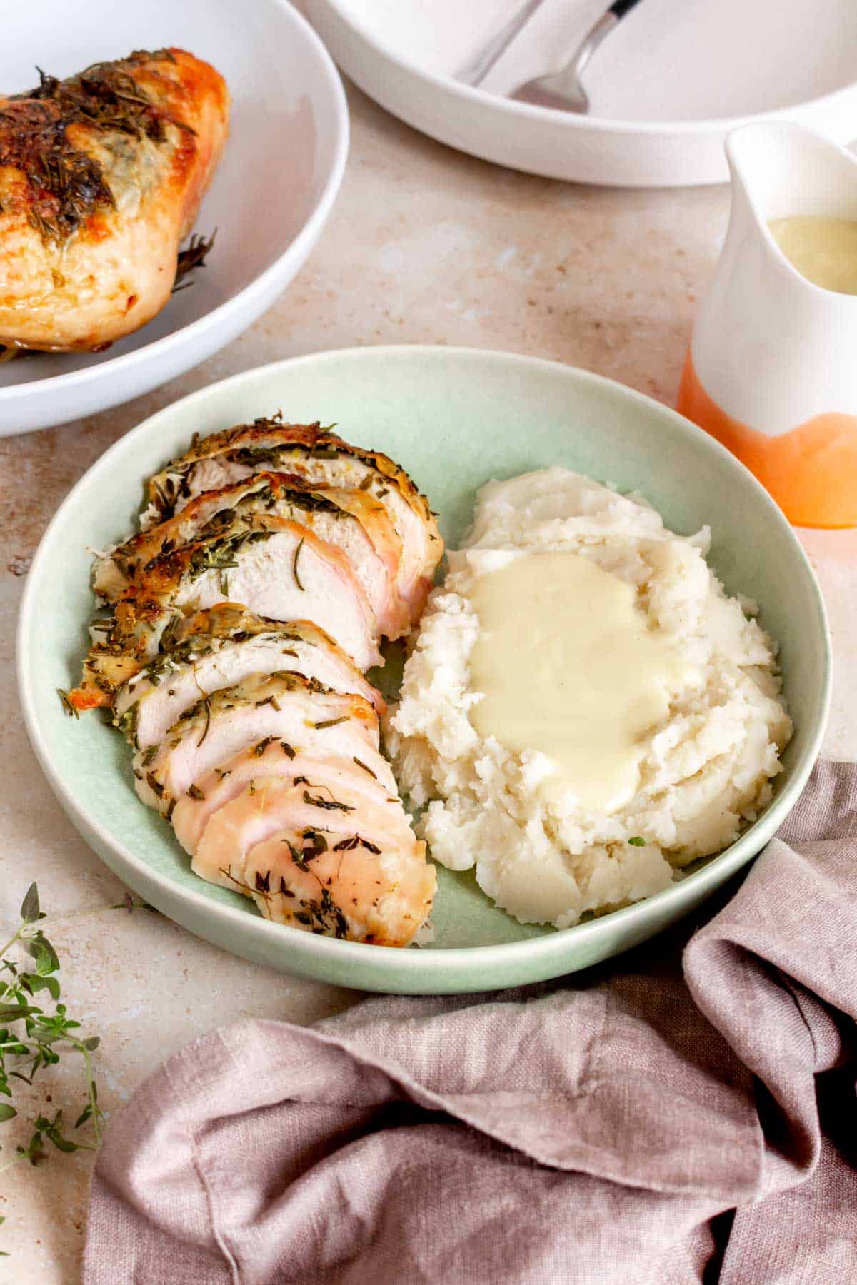 A plate with a serving of dutch oven turkey breast and mashed potatoes topped with gravy.