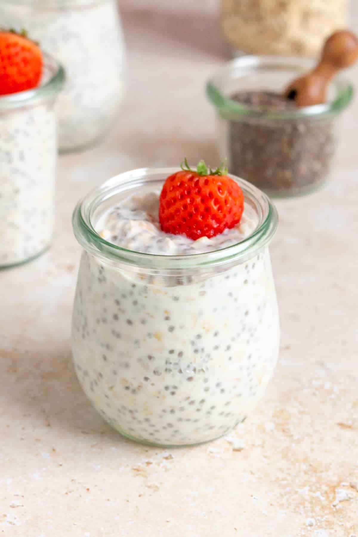 A jar of kefir overnight oats with a small strawberry on top.