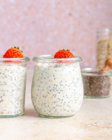 Two jars of kefir overnight oats topped with a mini strawberry.