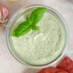 A jar of cottage cheese pesto with basil leaves on top as garnish.