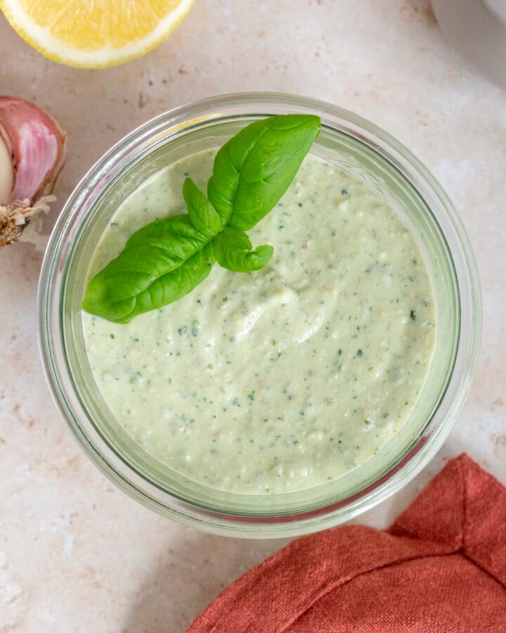 A jar of cottage cheese pesto with basil leaves on top as garnish.