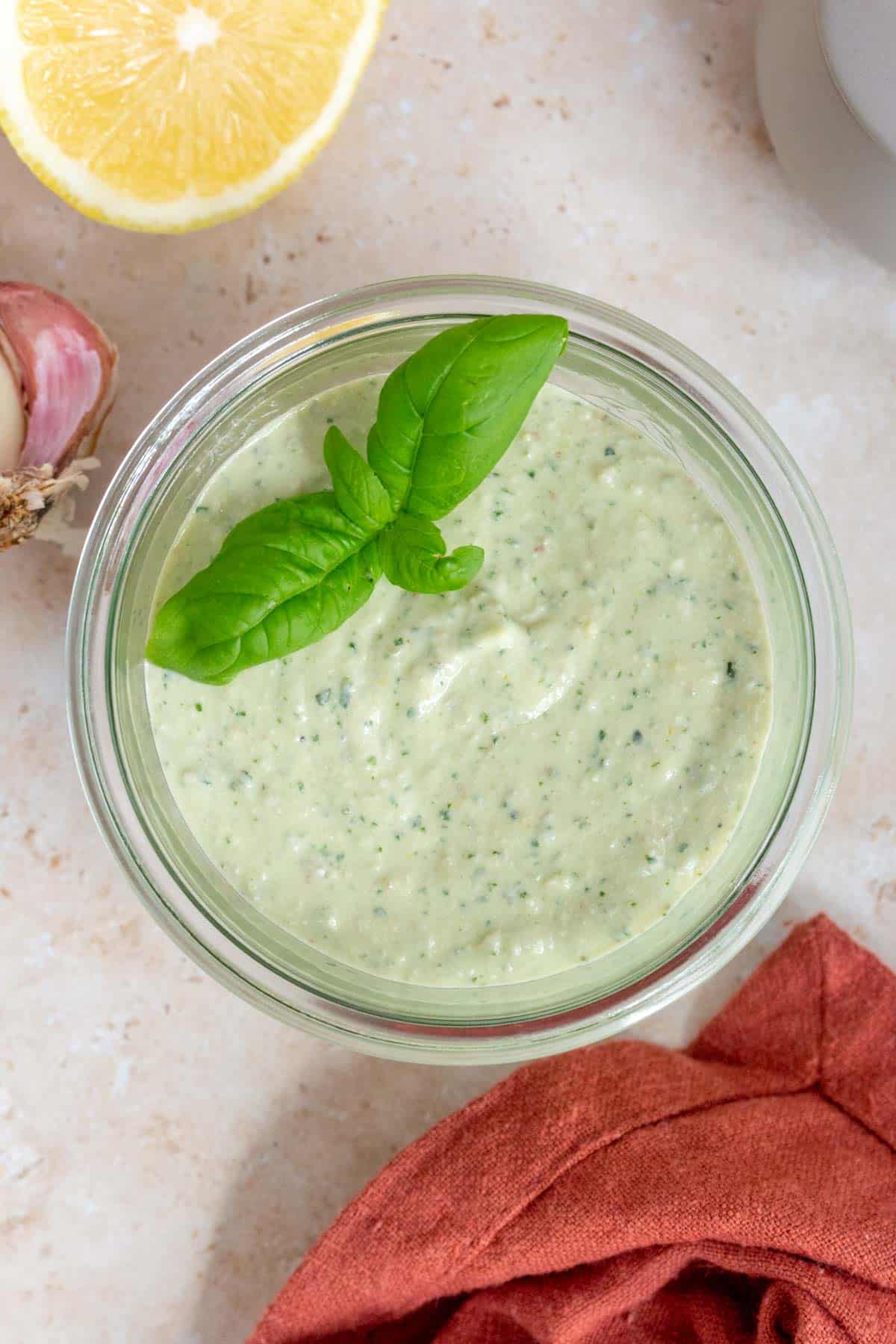 A jar of cottage cheese pesto with basil leaves on top as garnish.