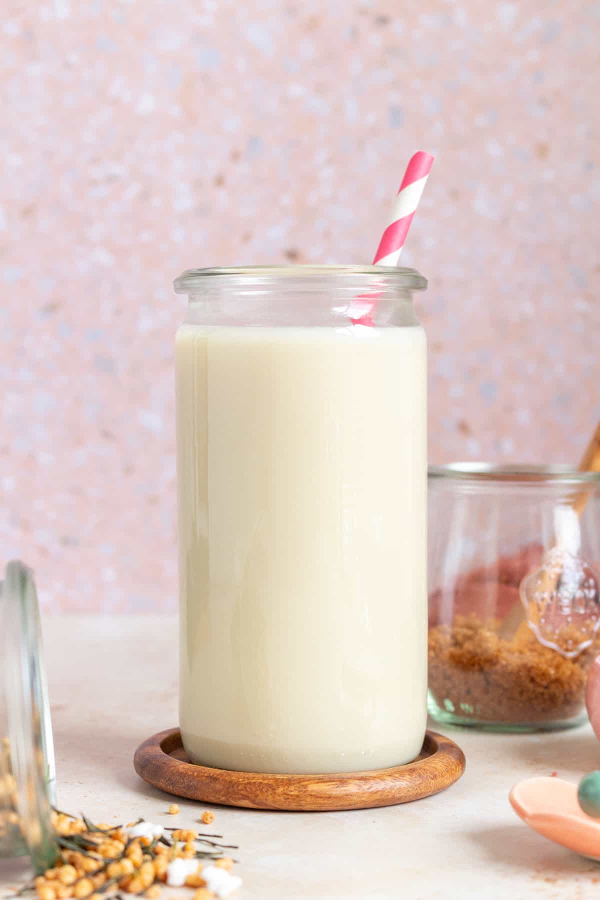 A glass of genmaicha milk tea with a pink striped straw.