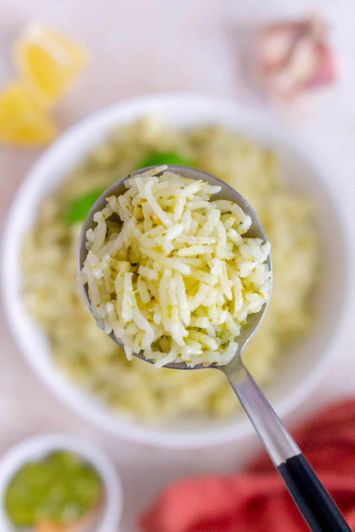 A spoonful of pesto rice lifted from a bowl.