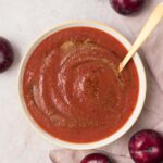 Overhead view of plum puree topped with more cinnamon and maple syrup. Plums surrounding it.