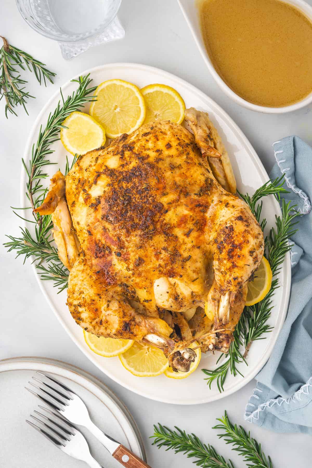 Overhead view of instant pot whole chicken on a platter surrounded by lemon slices and rosemary.