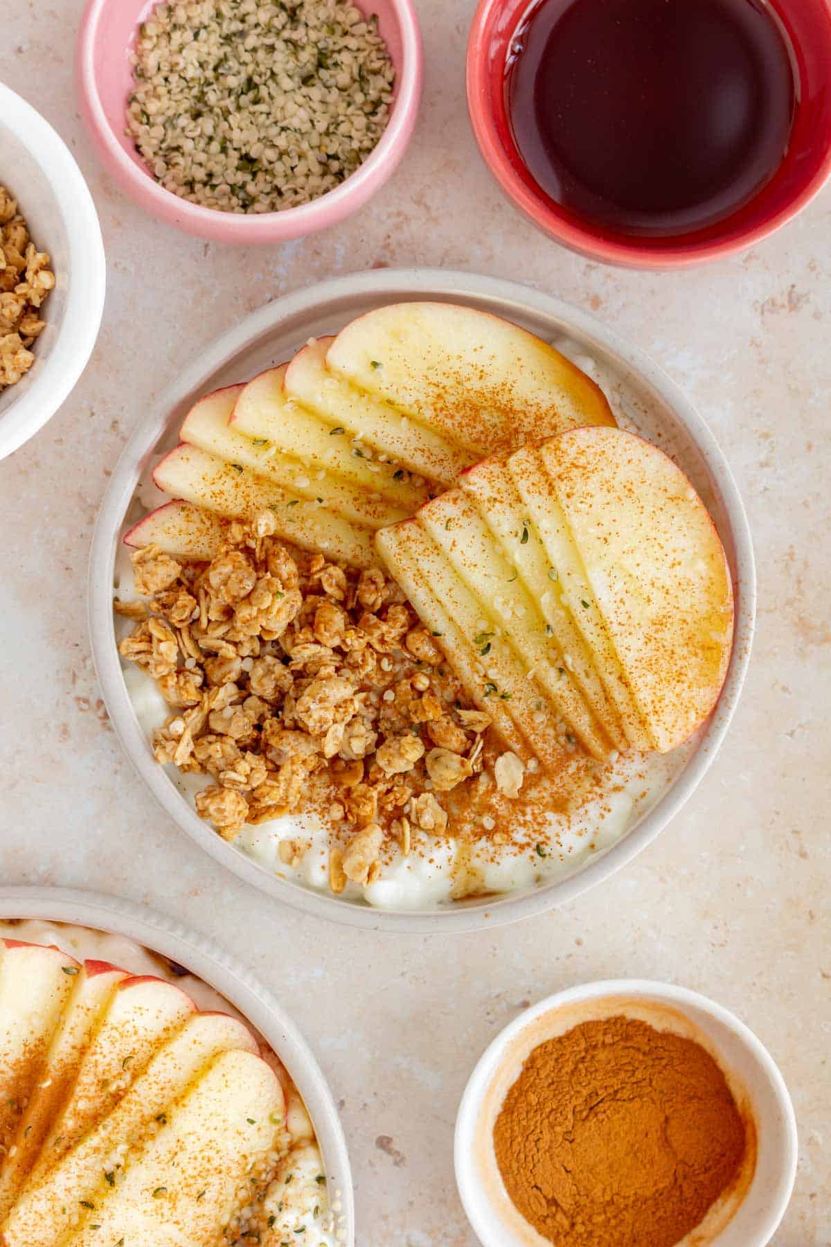 Overhead view of a cottage cheese apple cinnamon bowl surrounded by toppings in mini bowls.