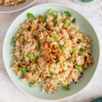Overhead view of a plate of garlic fried rice topped with green onions.