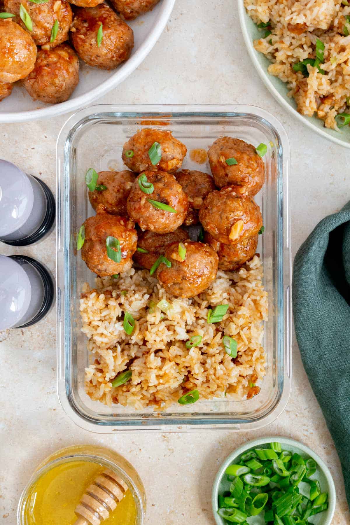 Overhead view of a meal prep container containing honey sriracha meatballs with mushrooms with a side of rice.