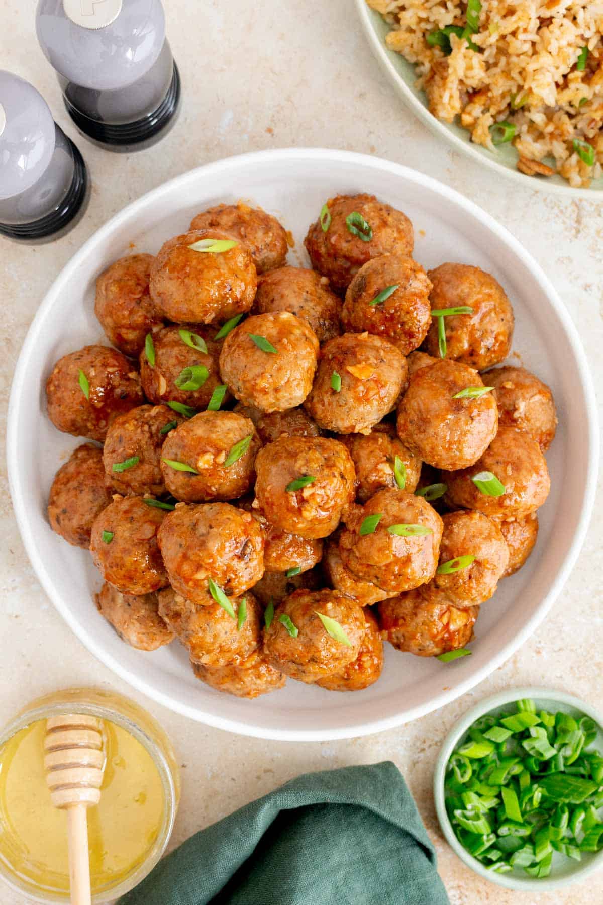 Overhead view of a plate of honey sriracha meatballs garnished with green onions.