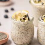 Jars of lemon poppy seed overnight oats topped with blueberries, lemon slices, and lemon zest.