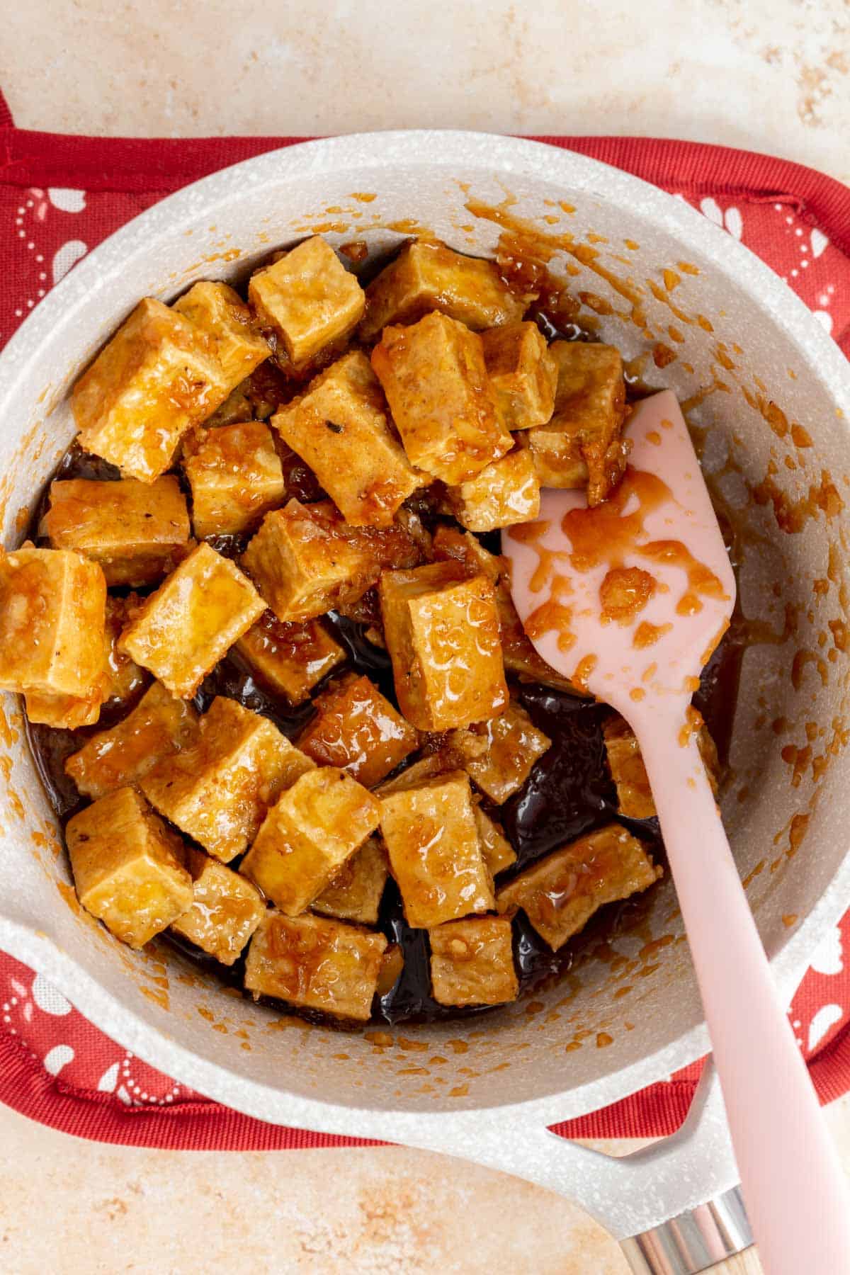 Crispy tofu coated in honey garlic sauce in the saucepan.