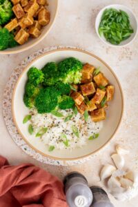 Overhead view of a bowl of honey garlic tofu with broccoli, rice, and green onions.