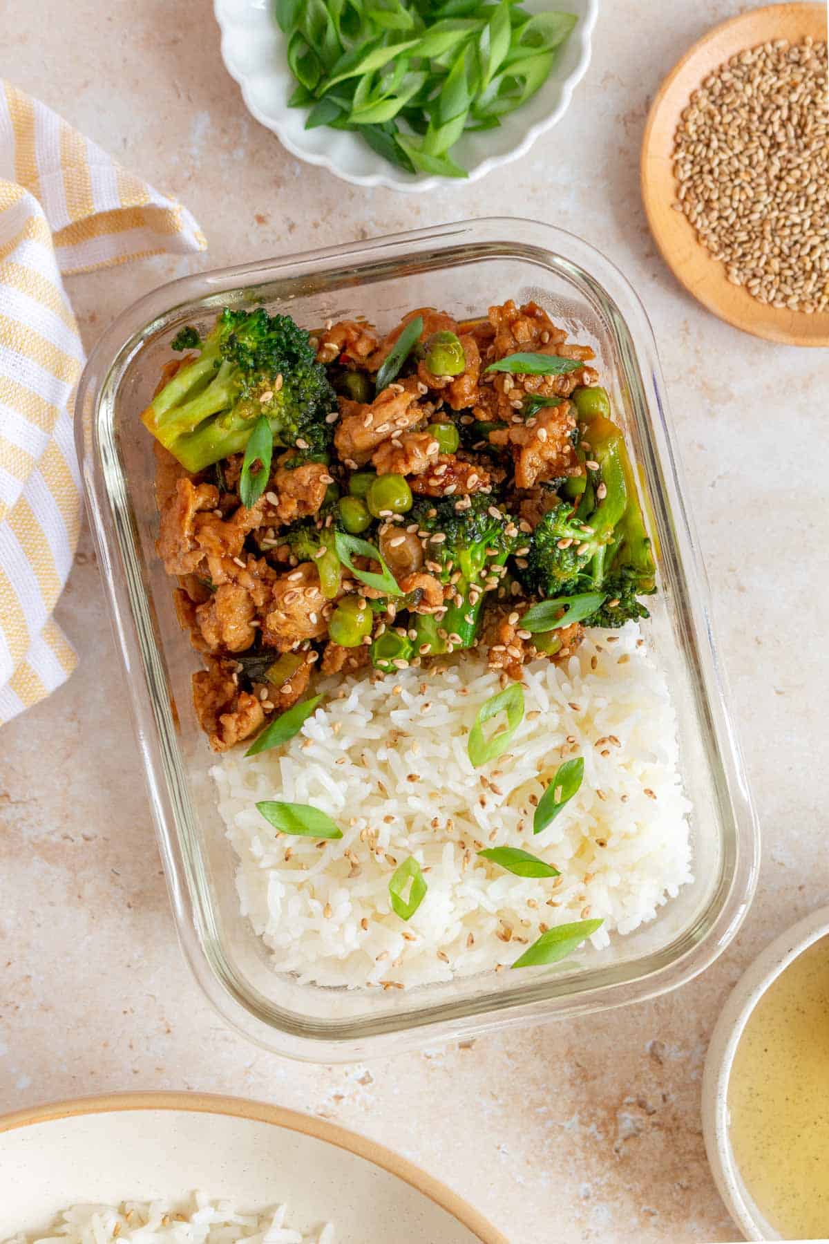 A meal prep container with honey sriracha ground chicken and broccoli in half and rice in the other.