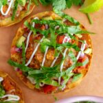 Overhead view of turkey tostadas on a serving board with cilantro and limes on the side.