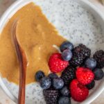 A close up view of a bowl of chia yogurt topped with peanut butter and fresh berries.