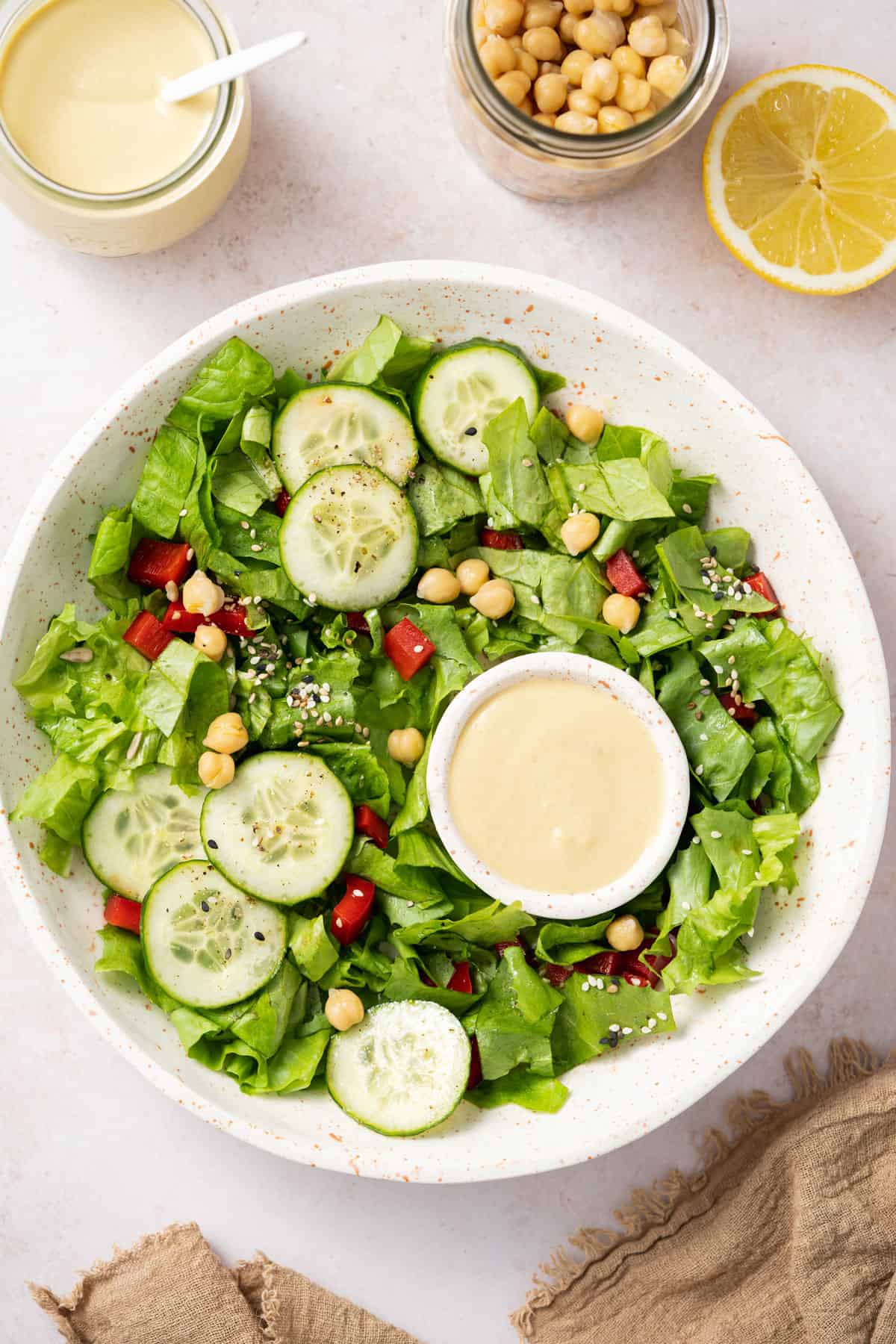 A bowl of salad with a small bowl of hummus dressing inside.