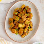 An oval platter of lemon pepper tofu topped with green onions.