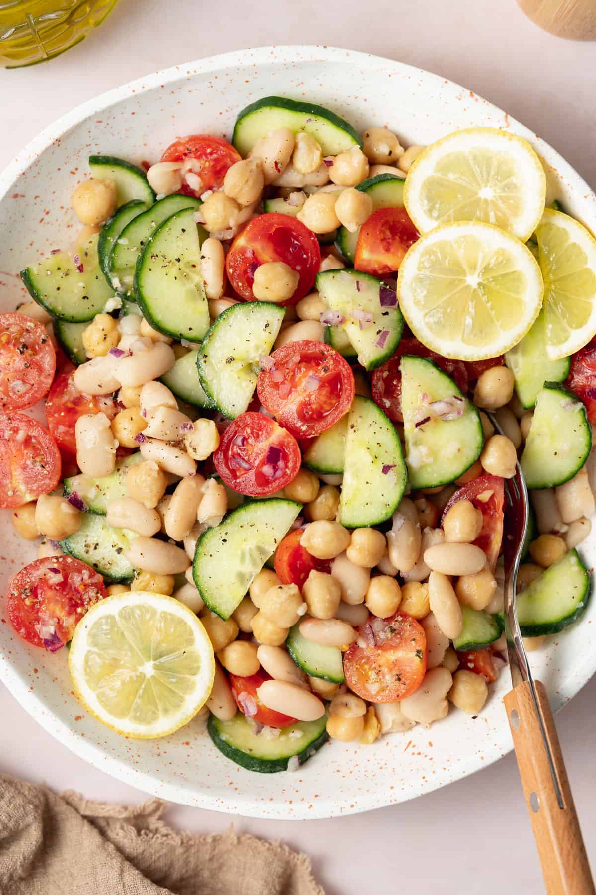 A close view of a bowl of no lettuce salad with lemon slices with a fork tucked in.