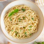 A bowl of butter lemon garlic pasta with basil on top.