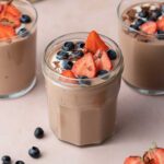 Jars of protein pudding topped with berries.